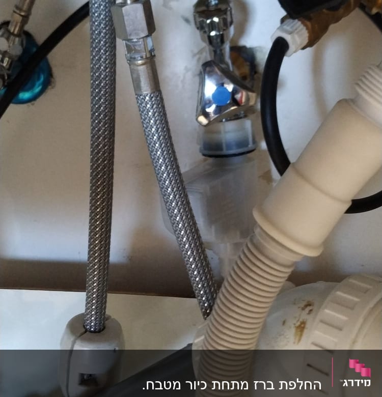 צינורות מתכת וגומי מתחת לכיור